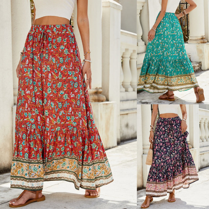 A high-waisted midi skirt with a bold digital print and a daring side slit, shown in a dark blue color. The skirt has snap buttons and is styled with a simple top.