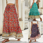 A high-waisted midi skirt with a bold digital print and a daring side slit, shown in a dark blue color. The skirt has snap buttons and is styled with a simple top.
