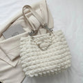 A close-up shot of a black bubble-textured tote bag with a chain detail, showcasing its unique surface and practical design.
