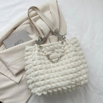 A close-up shot of a black bubble-textured tote bag with a chain detail, showcasing its unique surface and practical design.