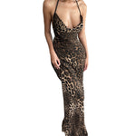 A woman confidently posing in a long, sleeveless maxi dress with a bold leopard print. The dress features a dramatic backless design and flows elegantly to the ground.