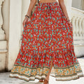 A high-waisted midi skirt with a bold digital print and a daring side slit, shown in a dark blue color. The skirt has snap buttons and is styled with a simple top.