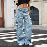 A pair of light blue, wide-leg, high-waist jeans with multiple pockets and pleated details. The jeans are displayed flat, showing the loose, straight-leg cut and zipper style.