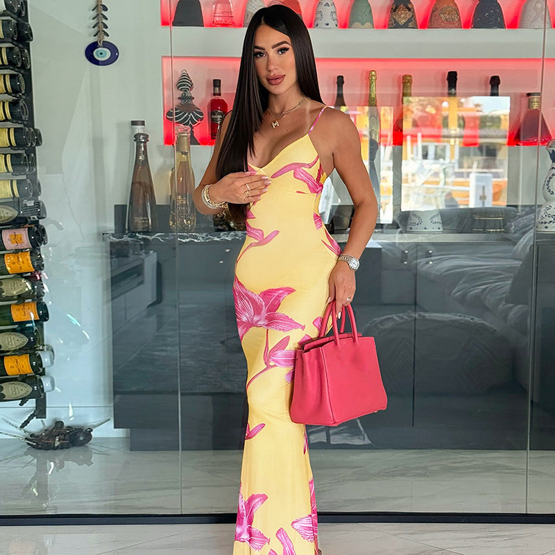 A yellow, printed strapless dress with a V-neck and a backless design. The dress is long and features a high-waist, shown laid flat to highlight the pattern and style.