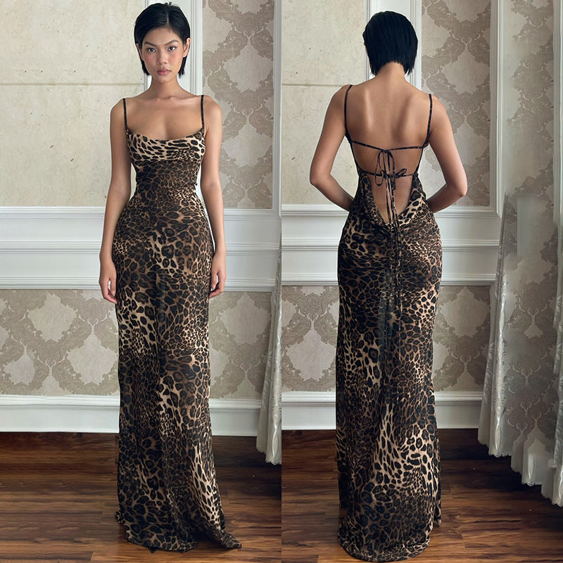 A woman confidently posing in a long, sleeveless maxi dress with a bold leopard print. The dress features a dramatic backless design and flows elegantly to the ground.