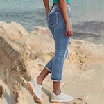 Woman wearing sky blue denim capri jeans with a flattering mid-rise fit and pocket details, standing confidently outdoors.