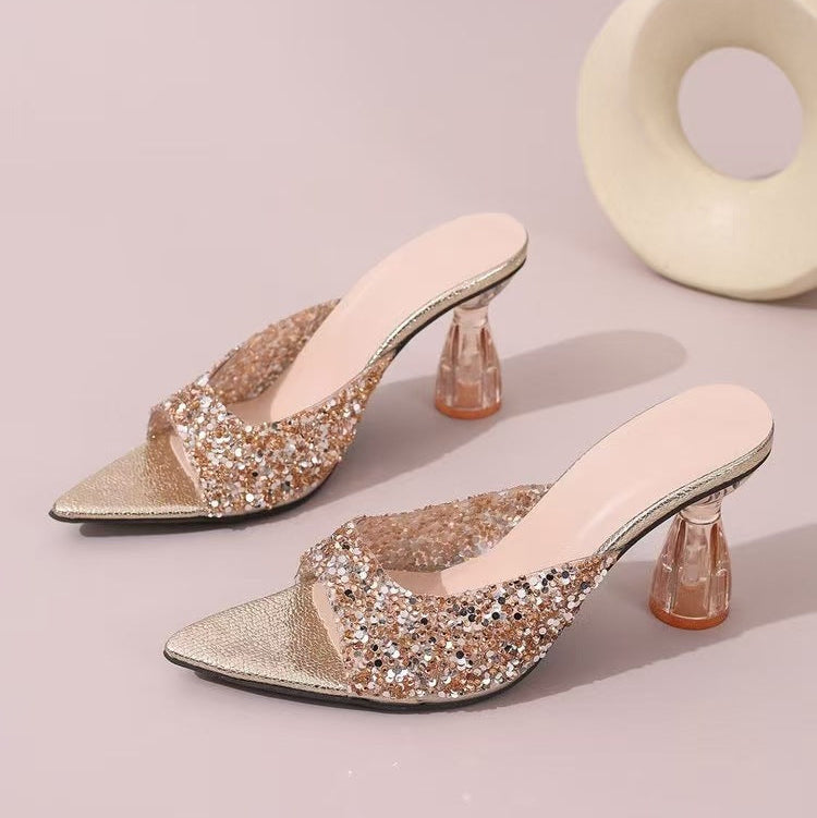 Pair of glittery high-heeled shoes on a light pink background