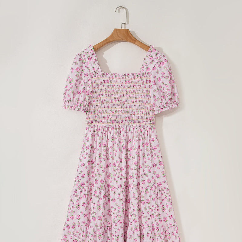 Pink floral dress on a hanger against a white background