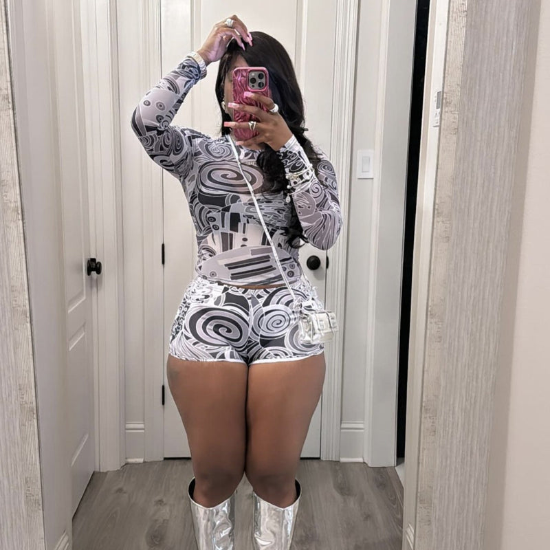 Person wearing a patterned outfit with silver knee-high boots in a room.