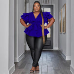 Woman wearing a blue top and black pants in a hallway