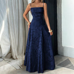 Woman wearing a navy blue floral dress standing against a neutral background